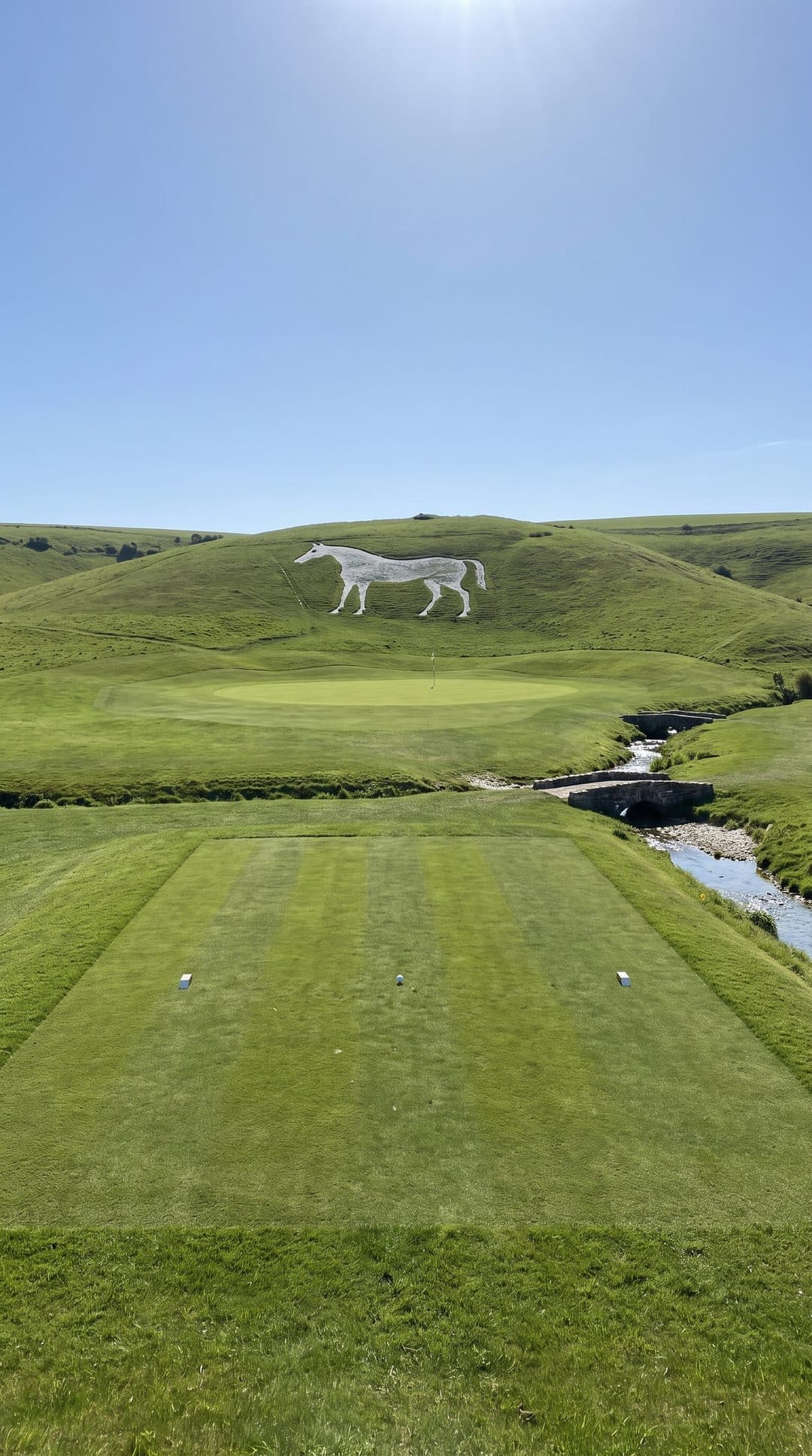 AI-imagined golf hole: a par 3 over a chalk stream with a white horse cut into the hill behind the green